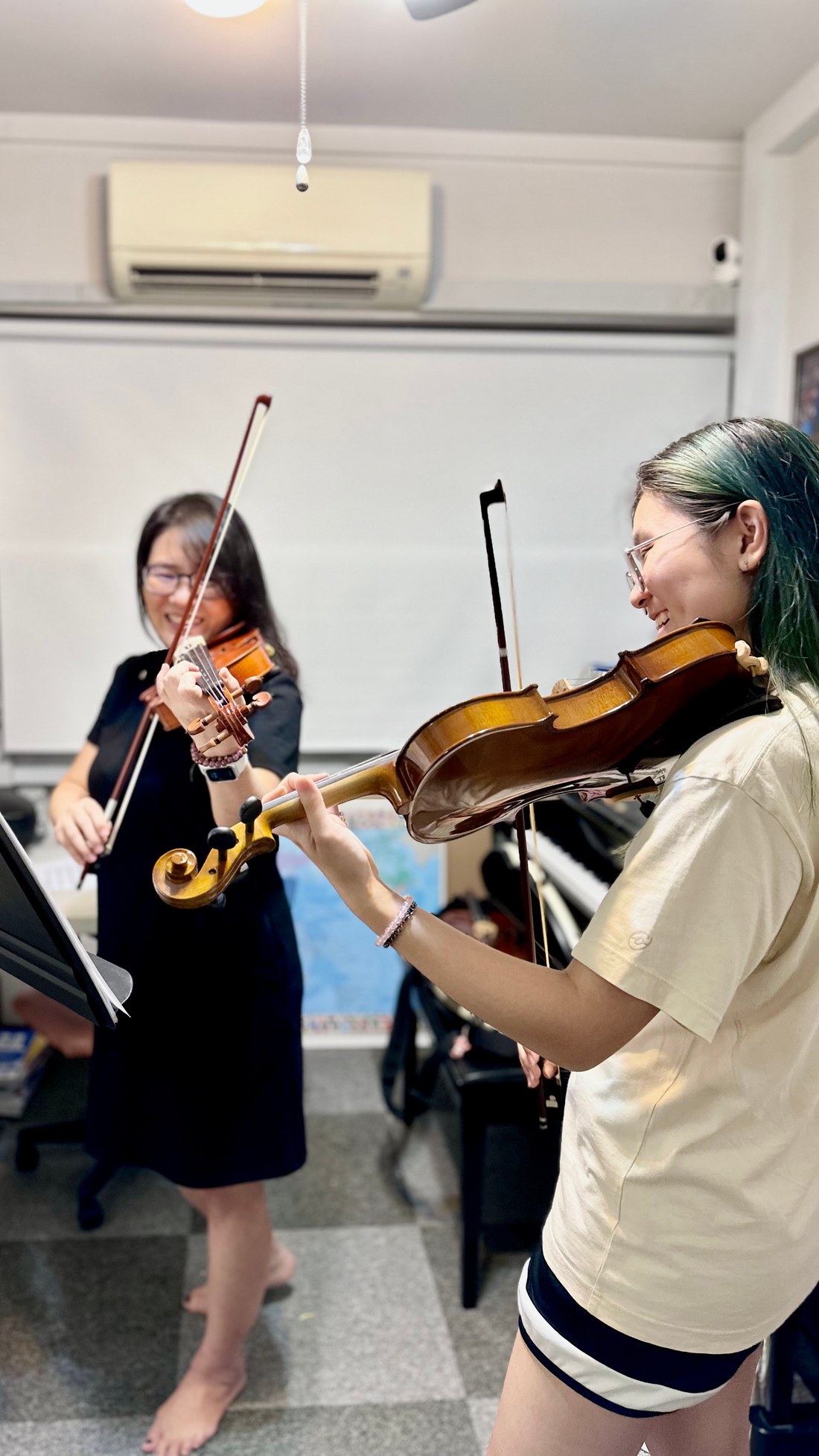 Two students playing violin together at the studio